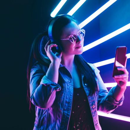 Sillhoutte of hip-hop girl with headphones at the neon light. Fashion portrait of modern young woman making selfie.