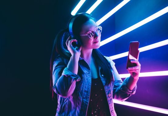 Sillhoutte of hip-hop girl with headphones at the neon light. Fashion portrait of modern young woman making selfie.